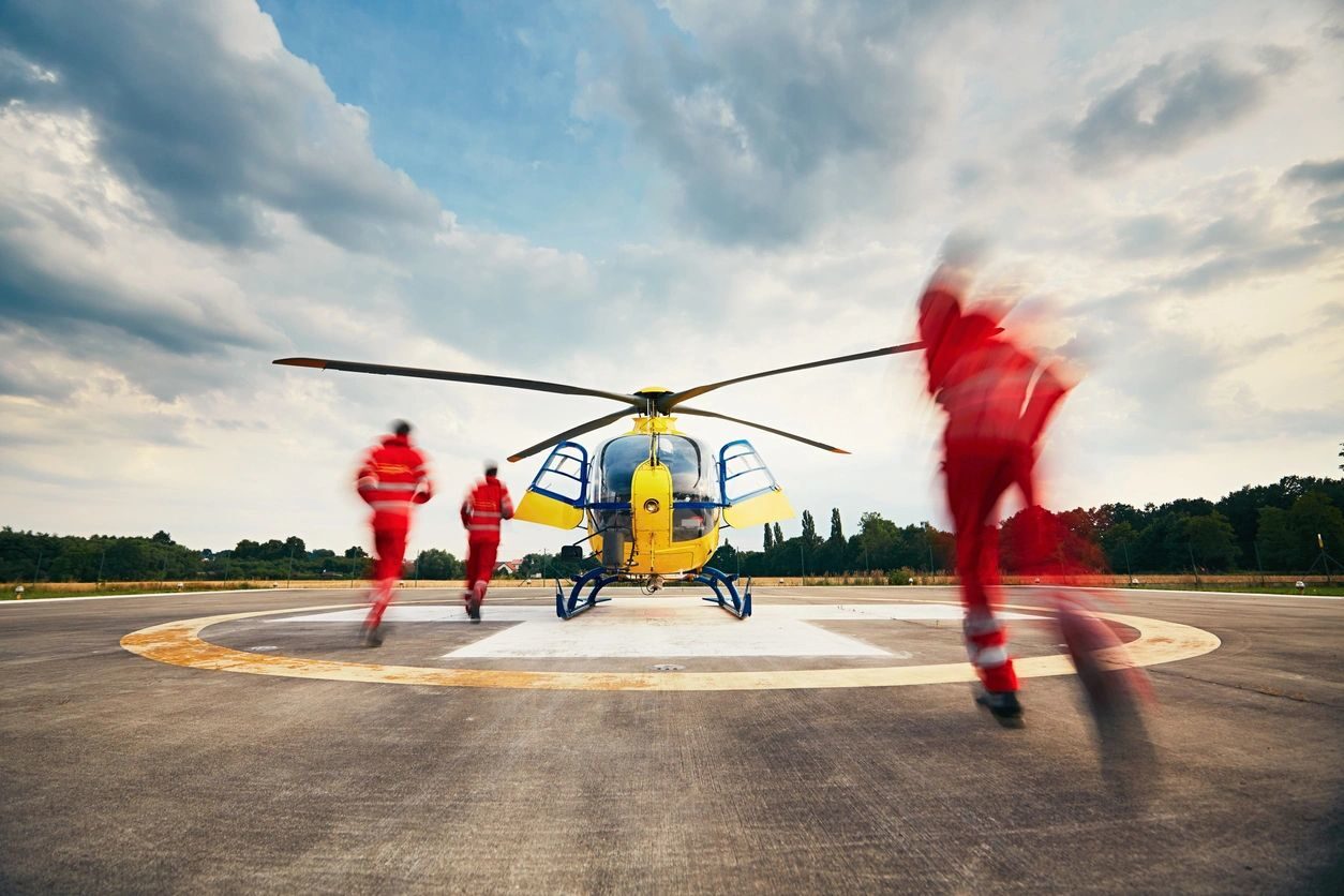 A helicopter is parked on the runway with three people.